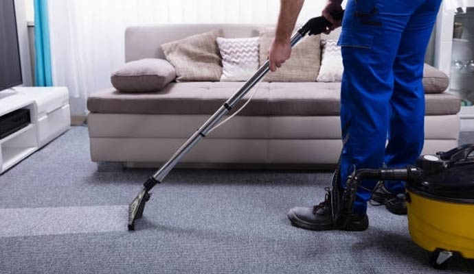 Technician cleaning a carpet in a living room with an extraction machine