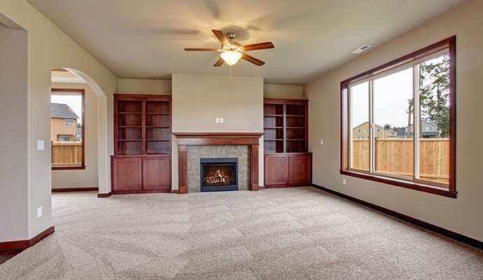 Carpeted living room with built-in shelves fireplace and large window