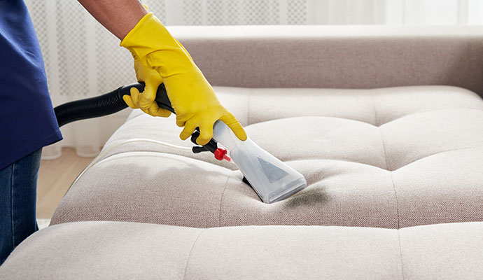 Professional cleaner using an extraction wand to deep clean a couch cushion