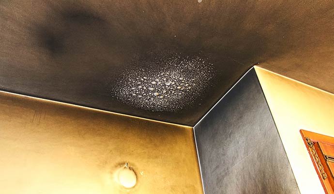 Heavy black soot and smoke damage on a residential ceiling and wall corner