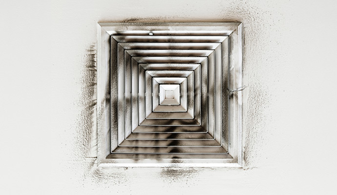 Ceiling air vent grille covered with soot