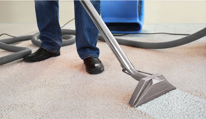 Technician cleaning carpet with extraction wand
