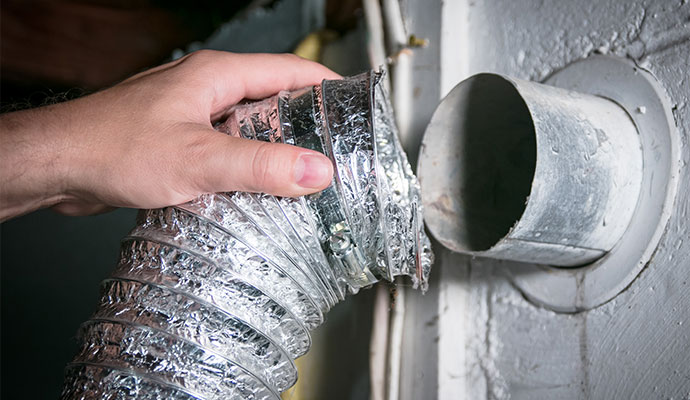 Technician connecting flexible dryer vent hose after cleaning