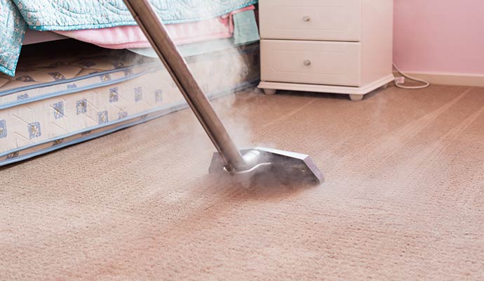 Technician steam cleaning carpet in bedroom
