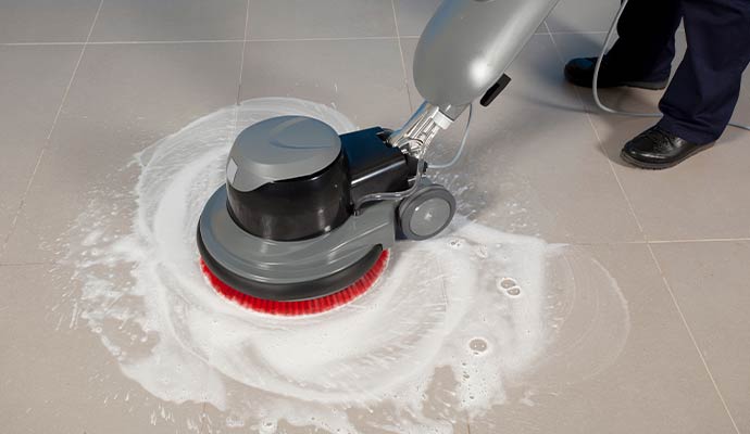 A professional floor buffer machine cleaning a tiled floor