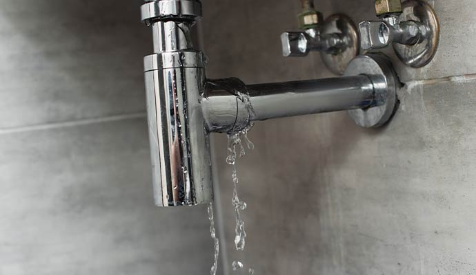 Water leaking from a trap pipe joint under a sink